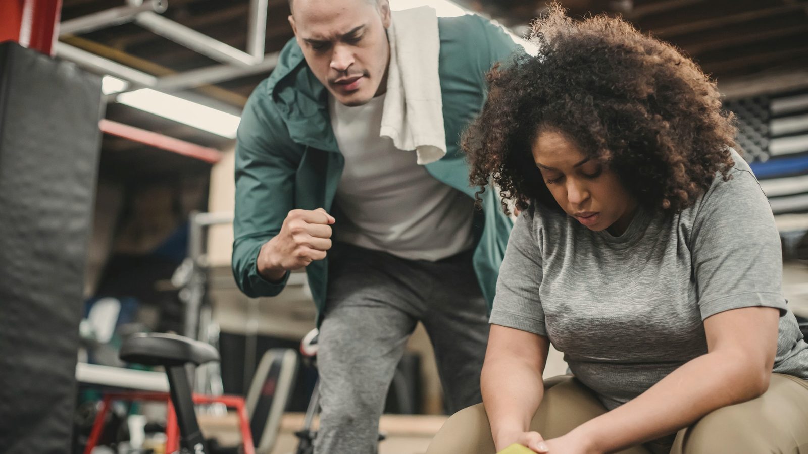 Trainer guiding a woman through a dumbbell exercise