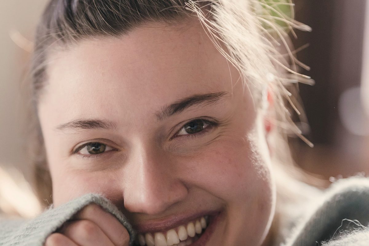 Happy woman sincerely smiling under sunlight in room