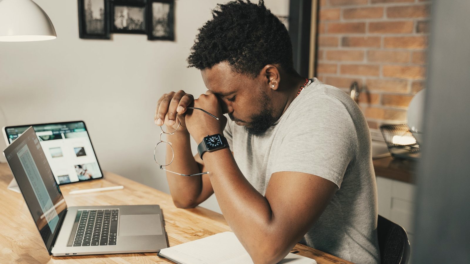 A tired man rubbing his eyes while sitting in front of his laptop