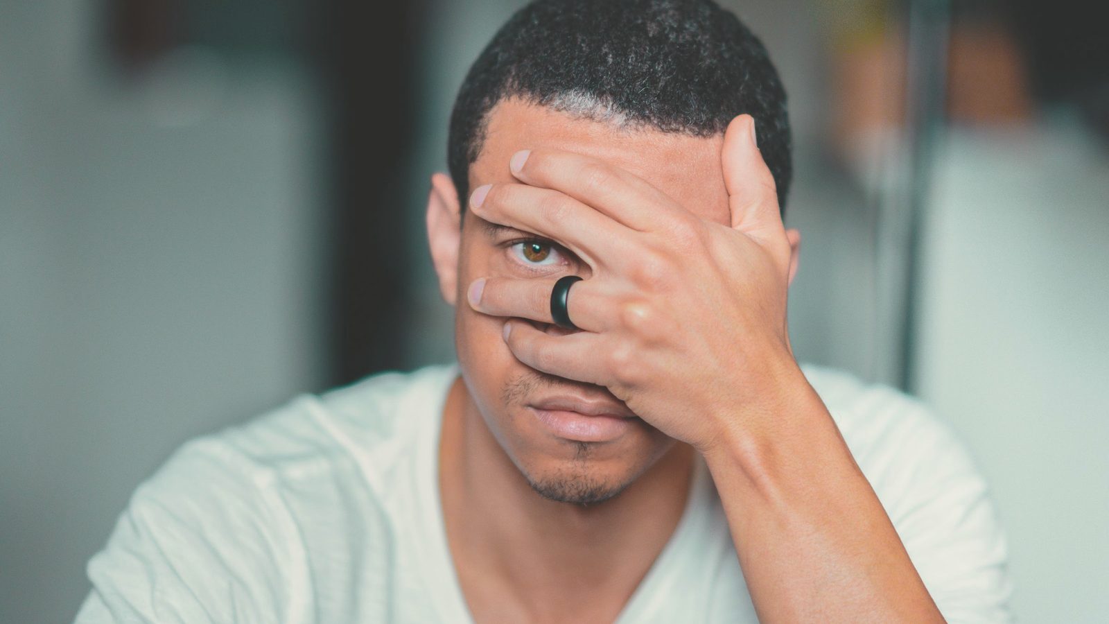 Exhausted man covering his face with his hand