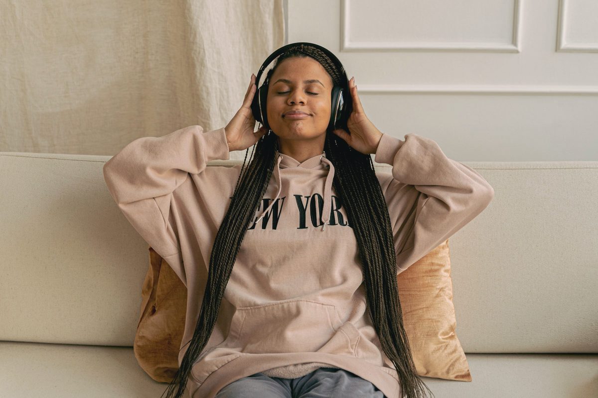 Young woman on a couch listening to music with her eyes closed