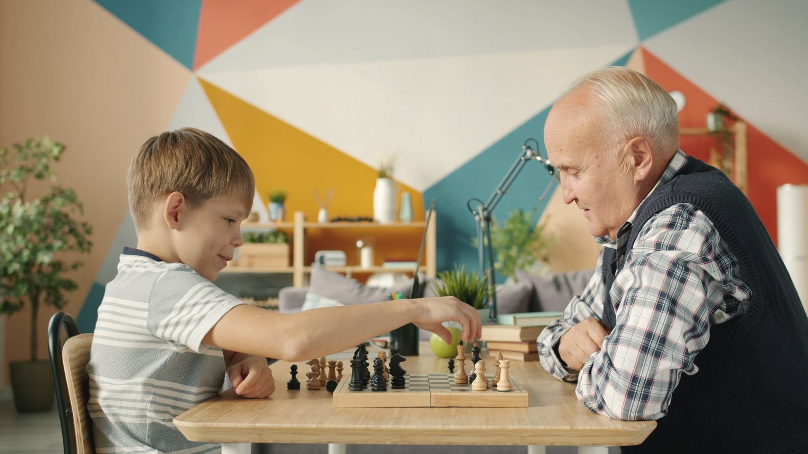 Grandfather and grandson playing chess indoors