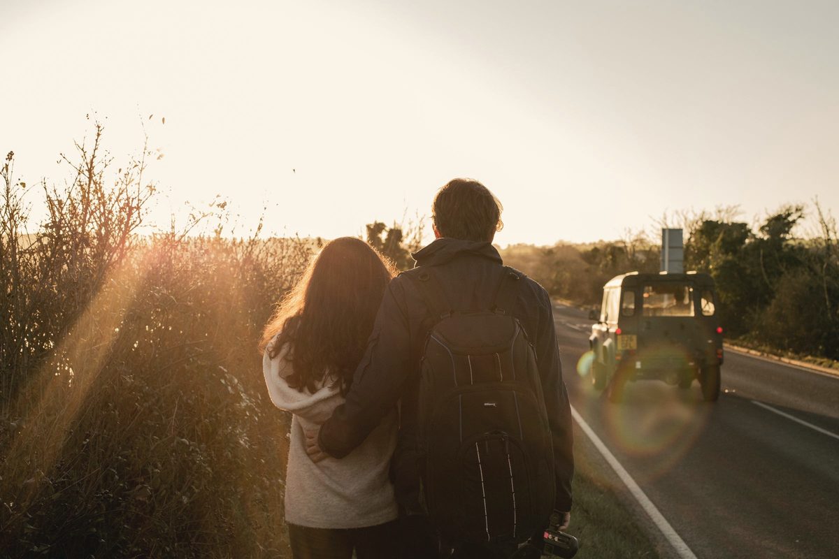 Couple walking beside the road at sunset