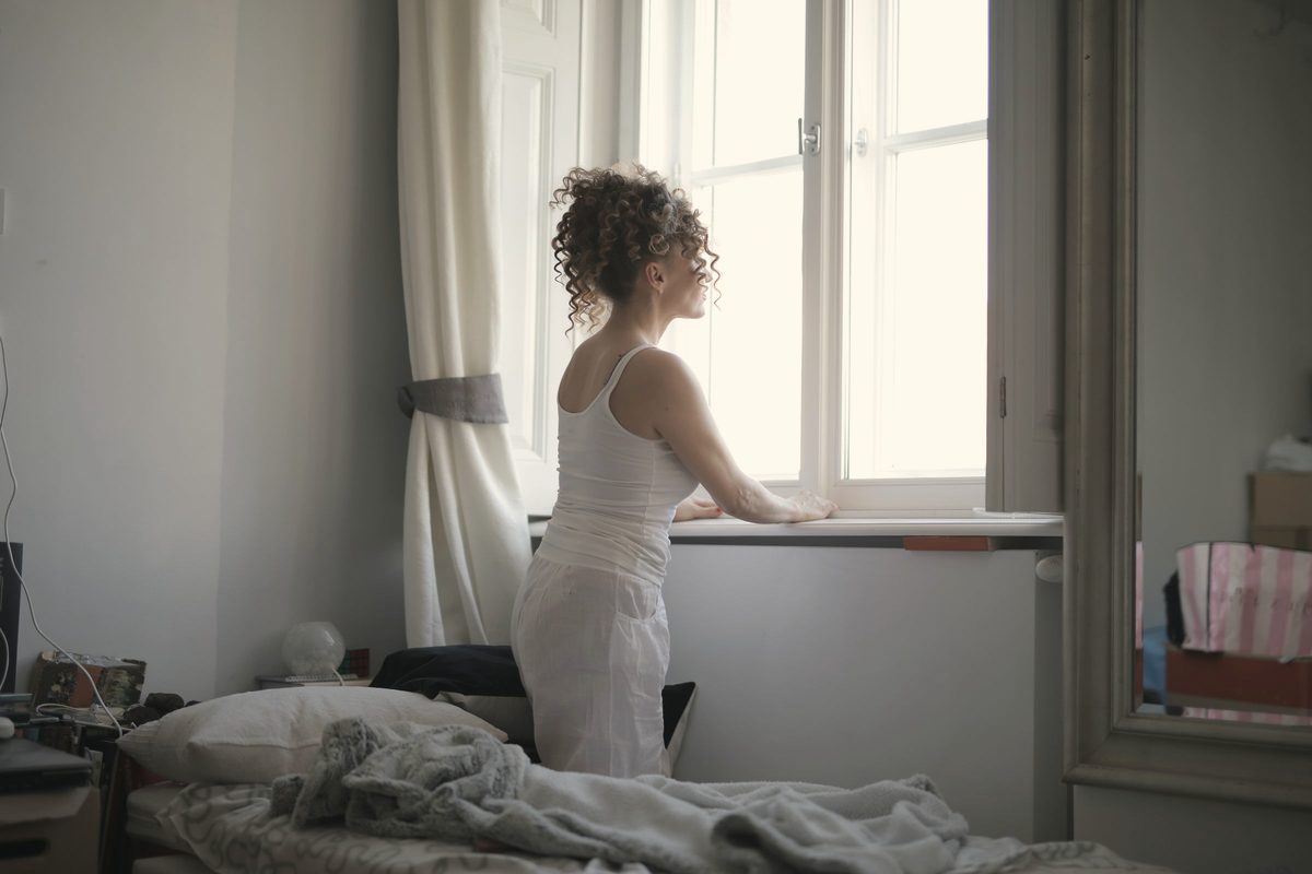Woman sitting quietly on her bed by the window