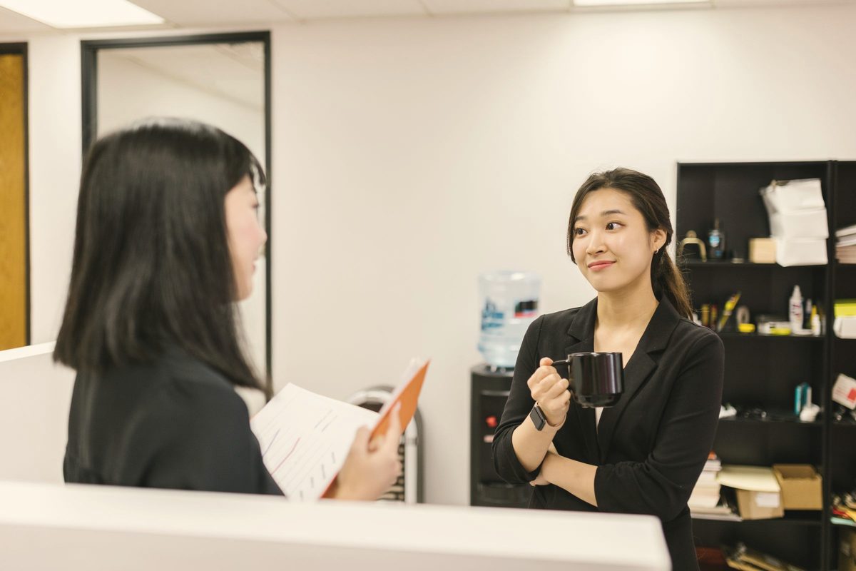 A woman listening to a coworker while holding a mug at an office