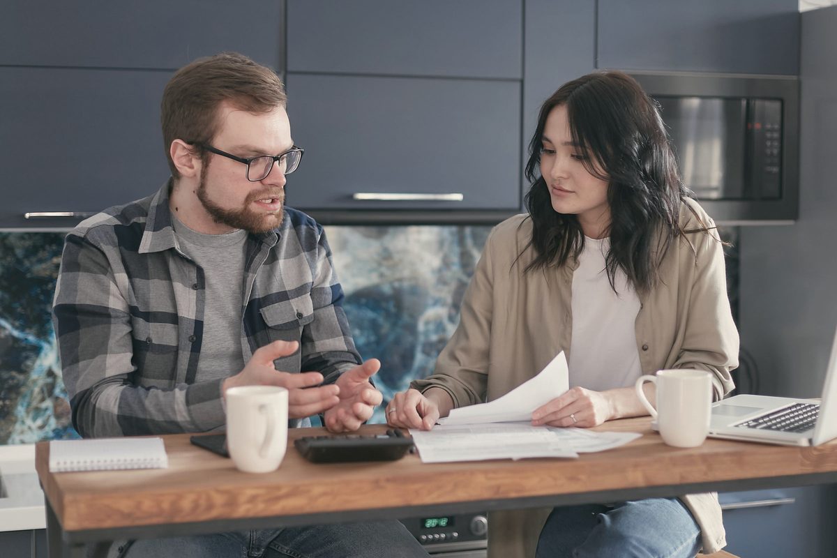A couple discussing their bills while sitting near the wooden table