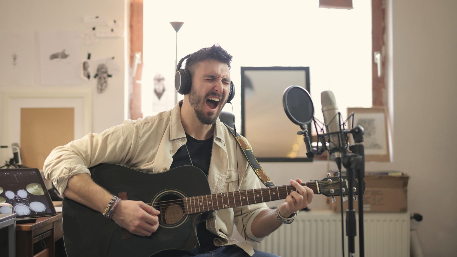 Man in brown button up shirt playing acoustic guitar