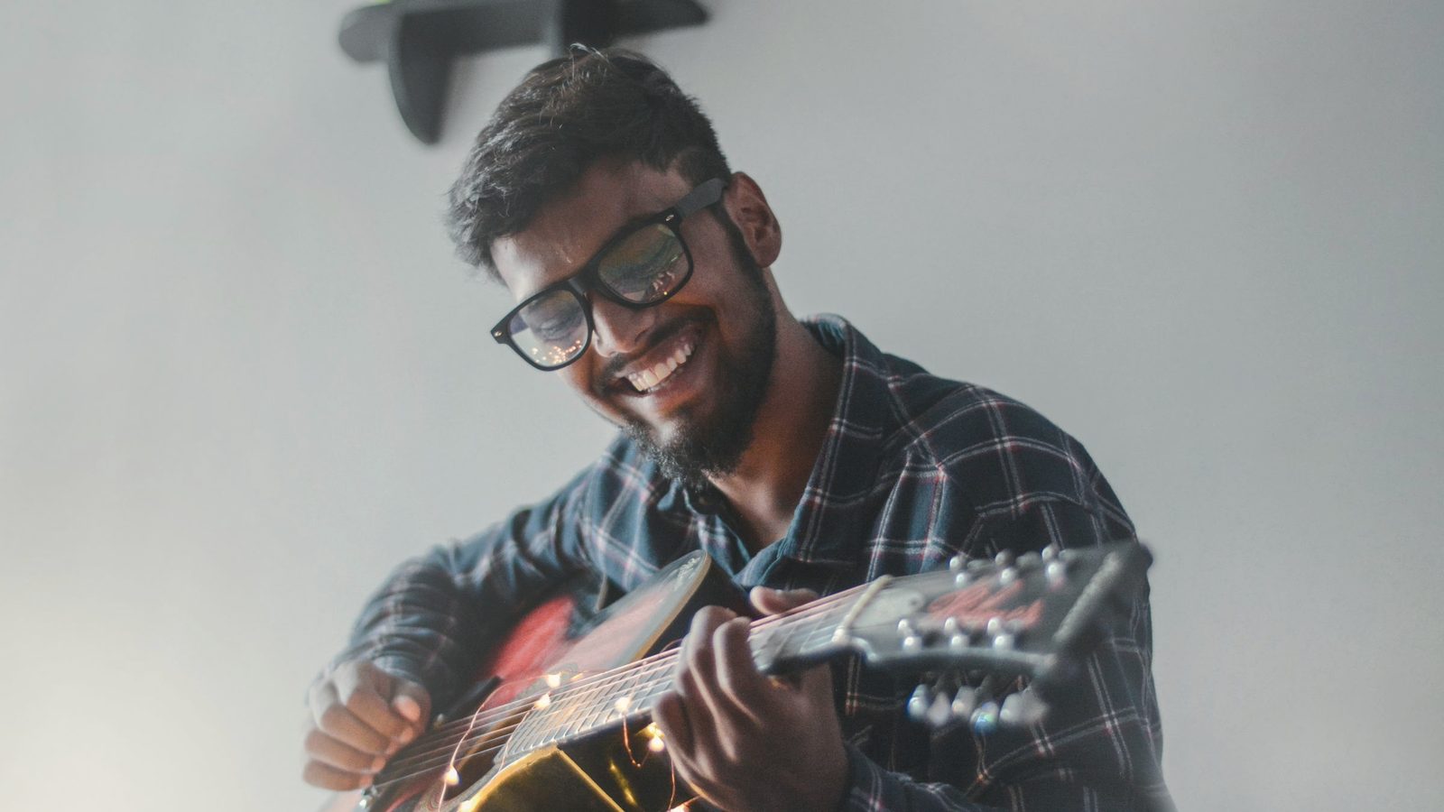 Smiling man absorbed in playing his guitar