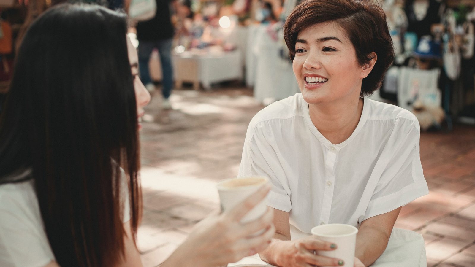 Cheerful women enjoying coffee and chatting in outdoors cafe