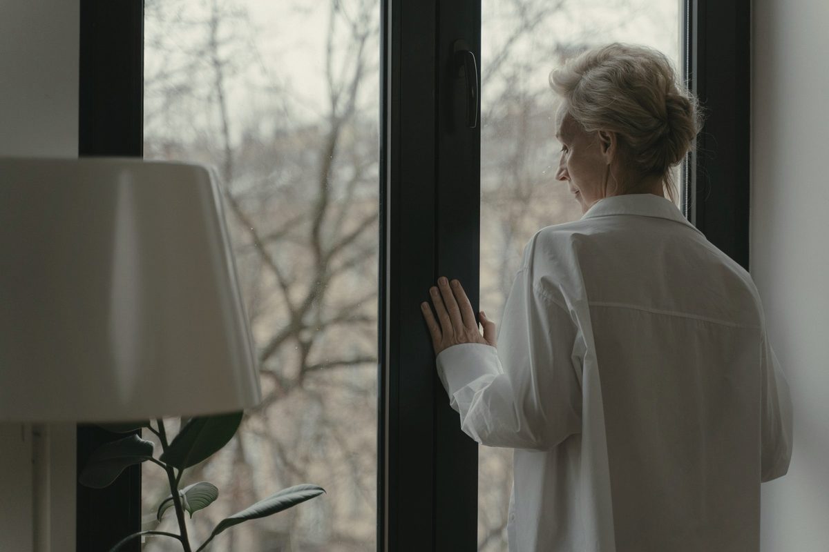 An elderly woman looking through the window
