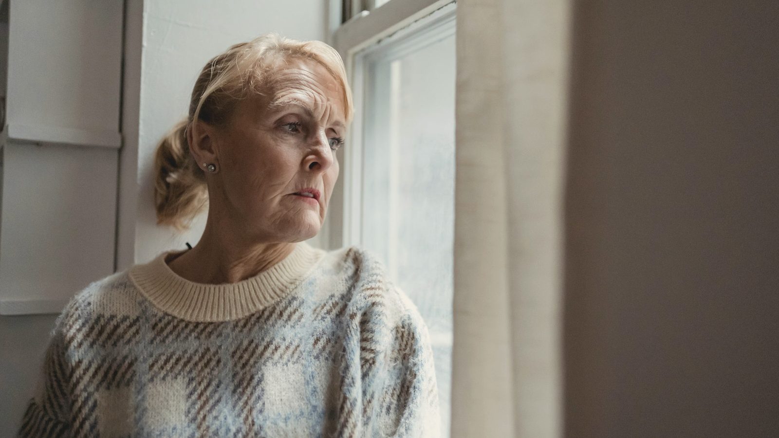 Pondering mature woman looking out window