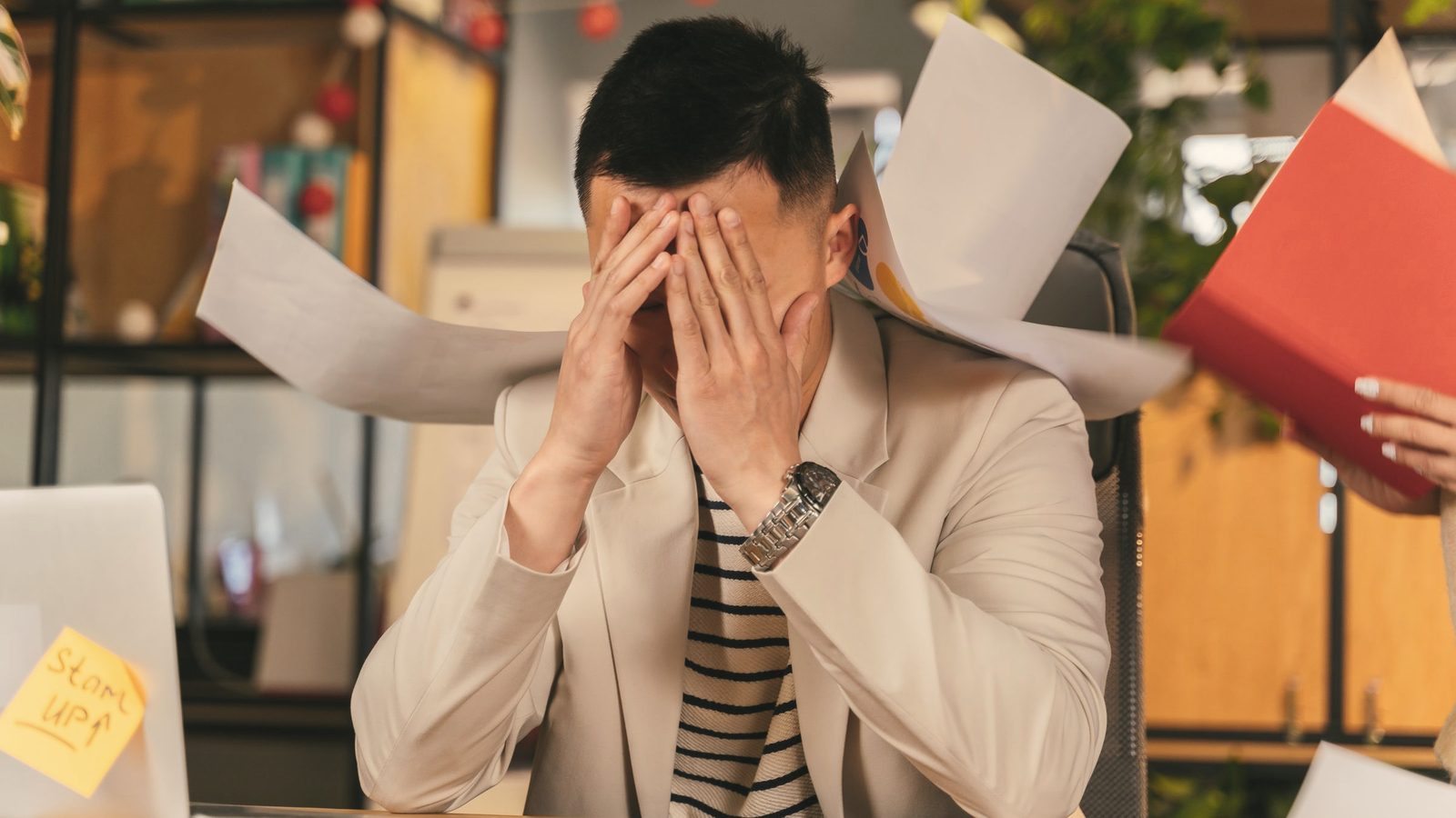 Overwhelmed man with his face in his hands at work