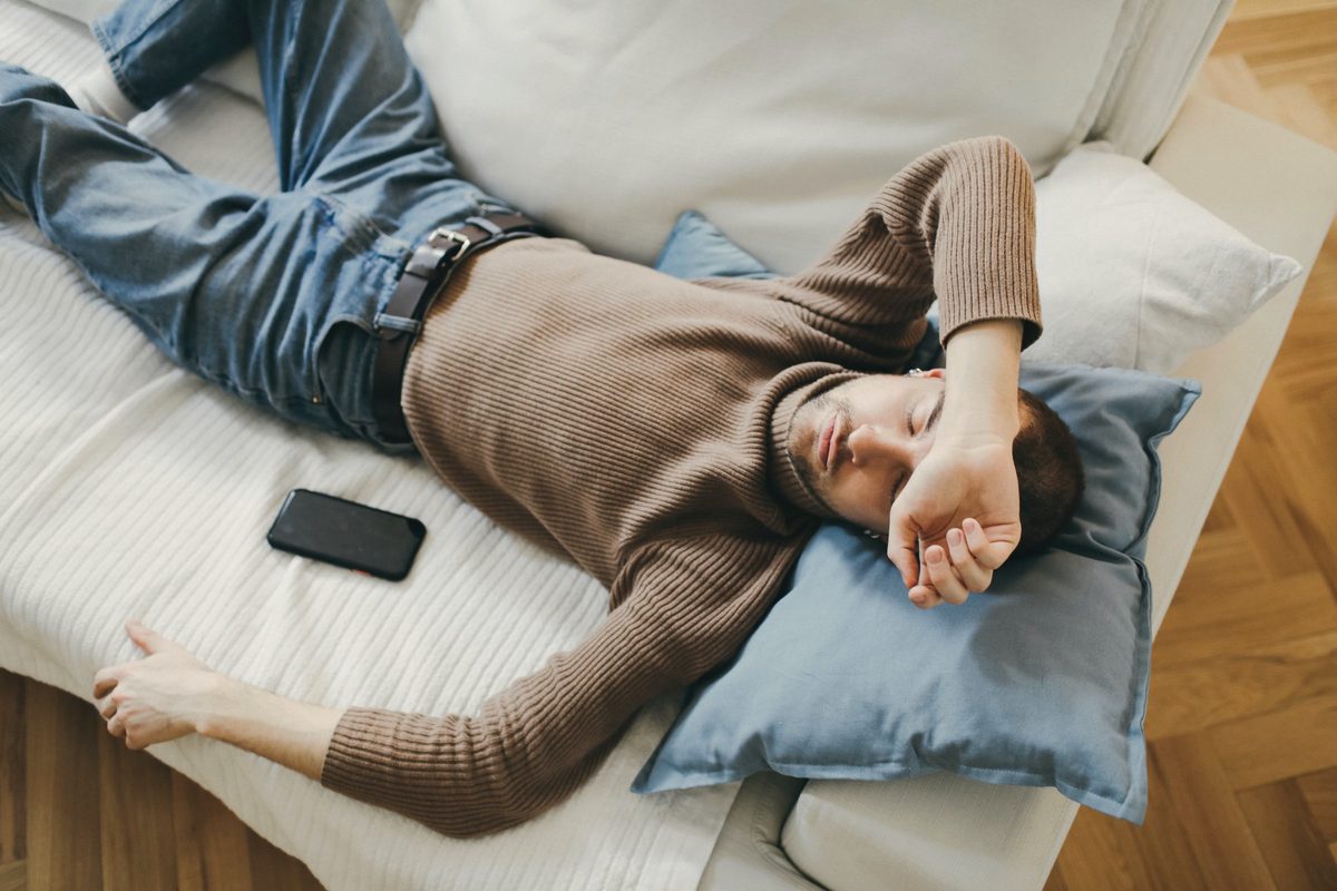 Man asleep on a sofa with his phone beside him