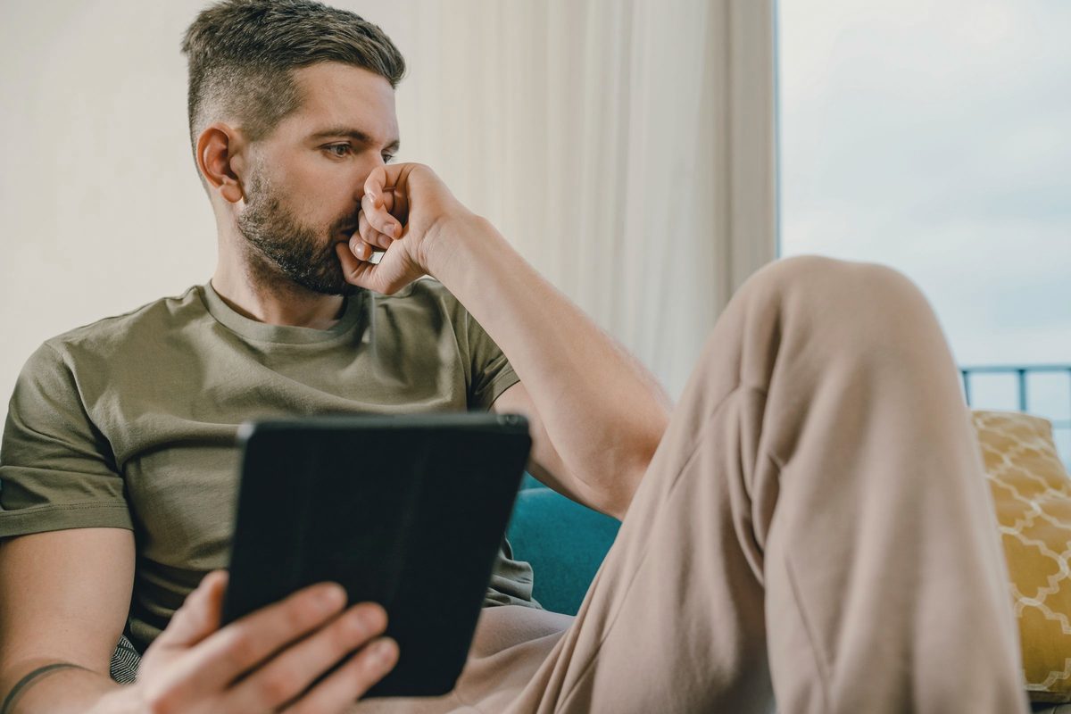 Worried man on a sofa holding a tablet