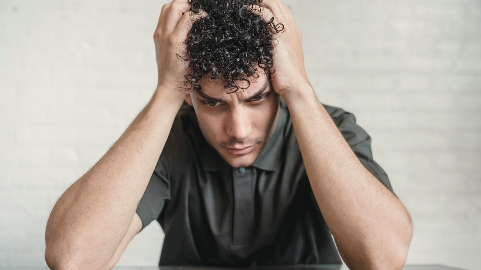 Young upset man sitting holding his head in hands