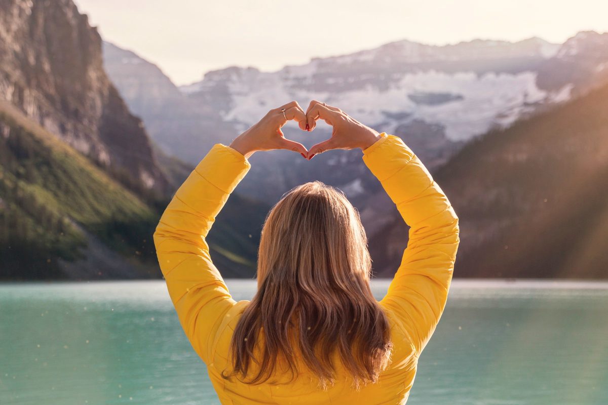 Woman in yellow long sleeve shirt with heart hand gesture