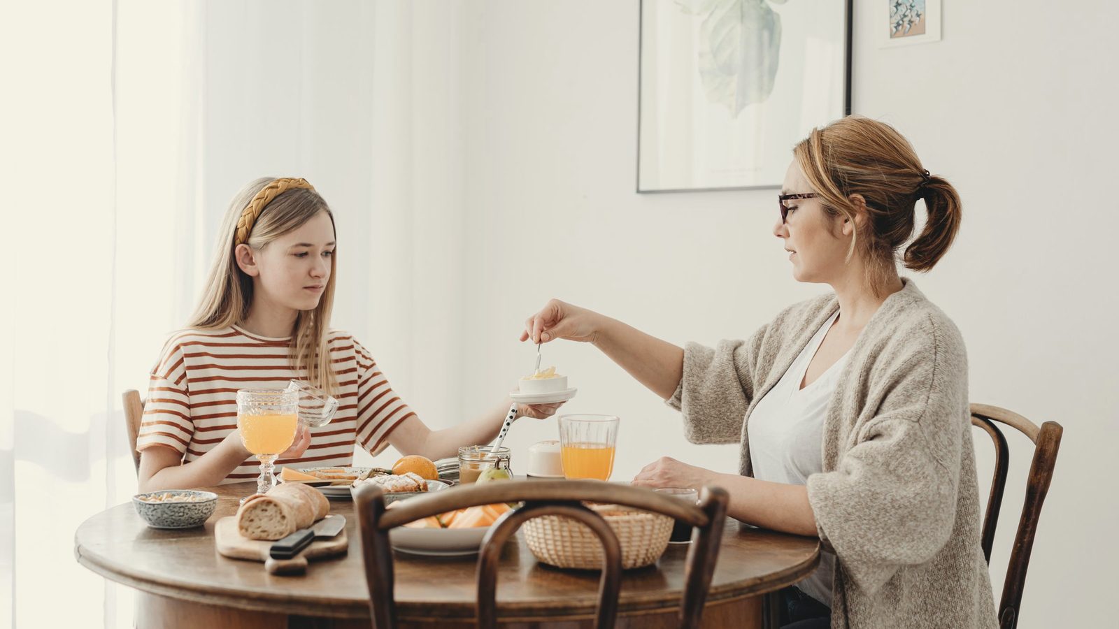 Woman and a girl eating breakfast at a wooden table