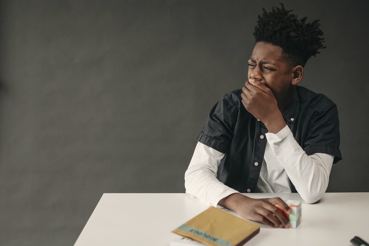 Young person yawning at a desk