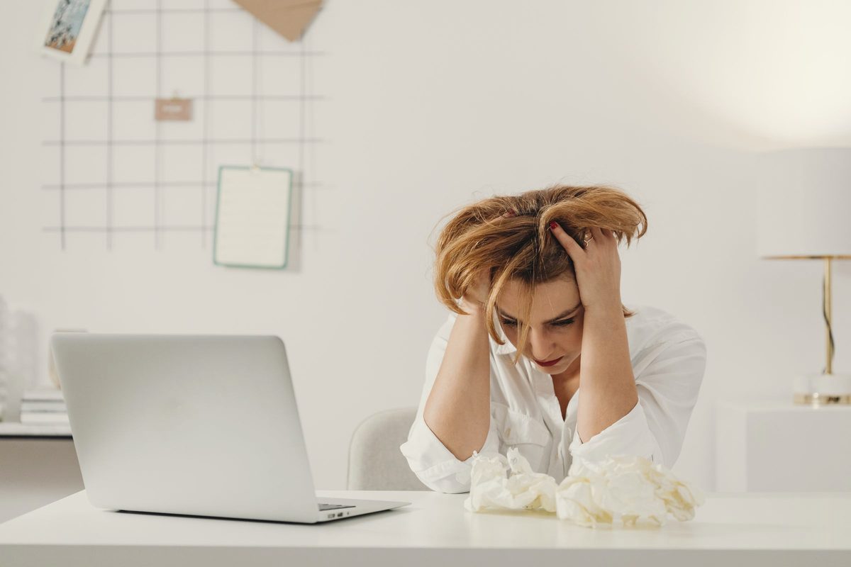 Stressed woman with her hands in her hair at her desk