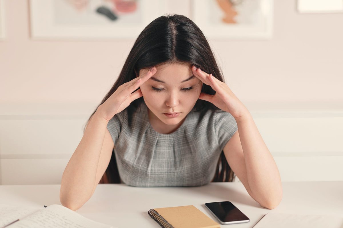 Anxious woman holding her head in her hands at a table