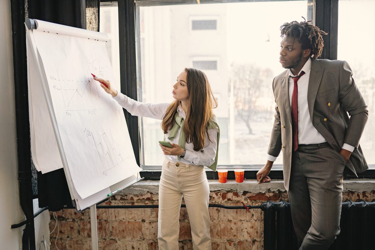 Woman presenting at a flip chart while a colleague watches