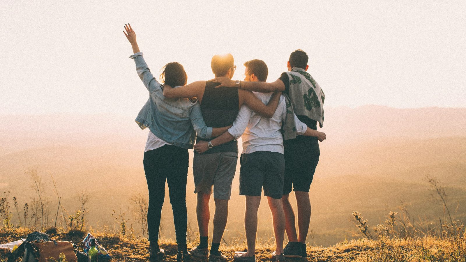 Friends standing arm in arm at sunset in the hills
