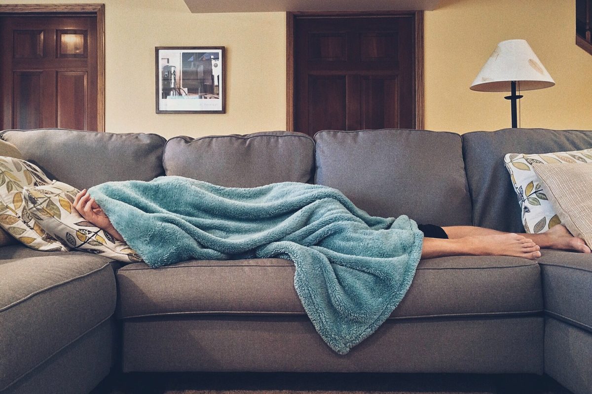 Person resting on a sofa under a blanket