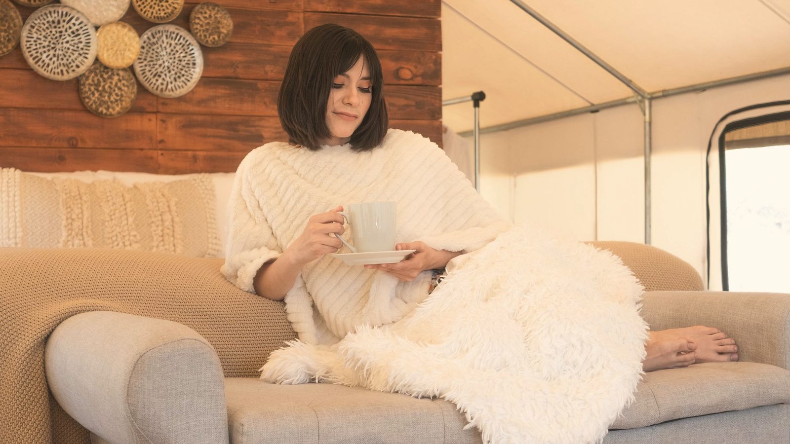 Woman sitting on sofa covering her legs with a fur blanket