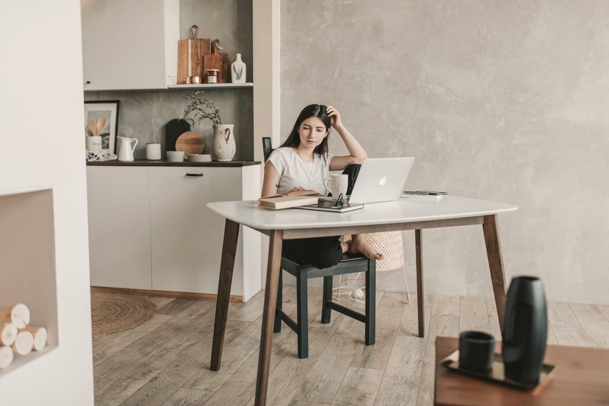 Woman with her laptop and books at a home desk