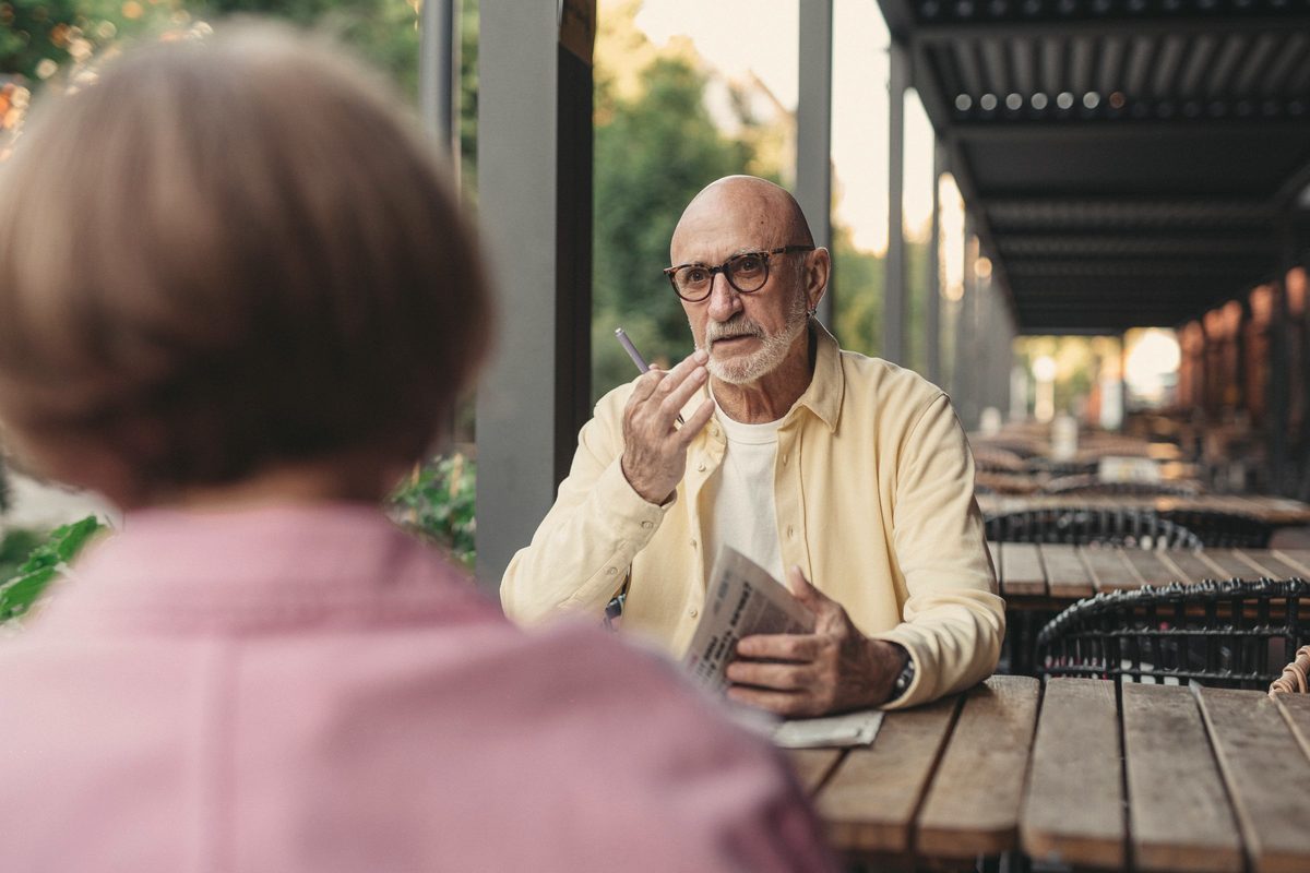 Elderly couple talking to each other at the wooden table