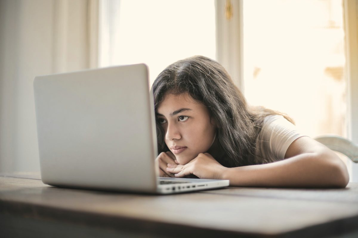 Weary young woman leaning on the table in front of her laptop