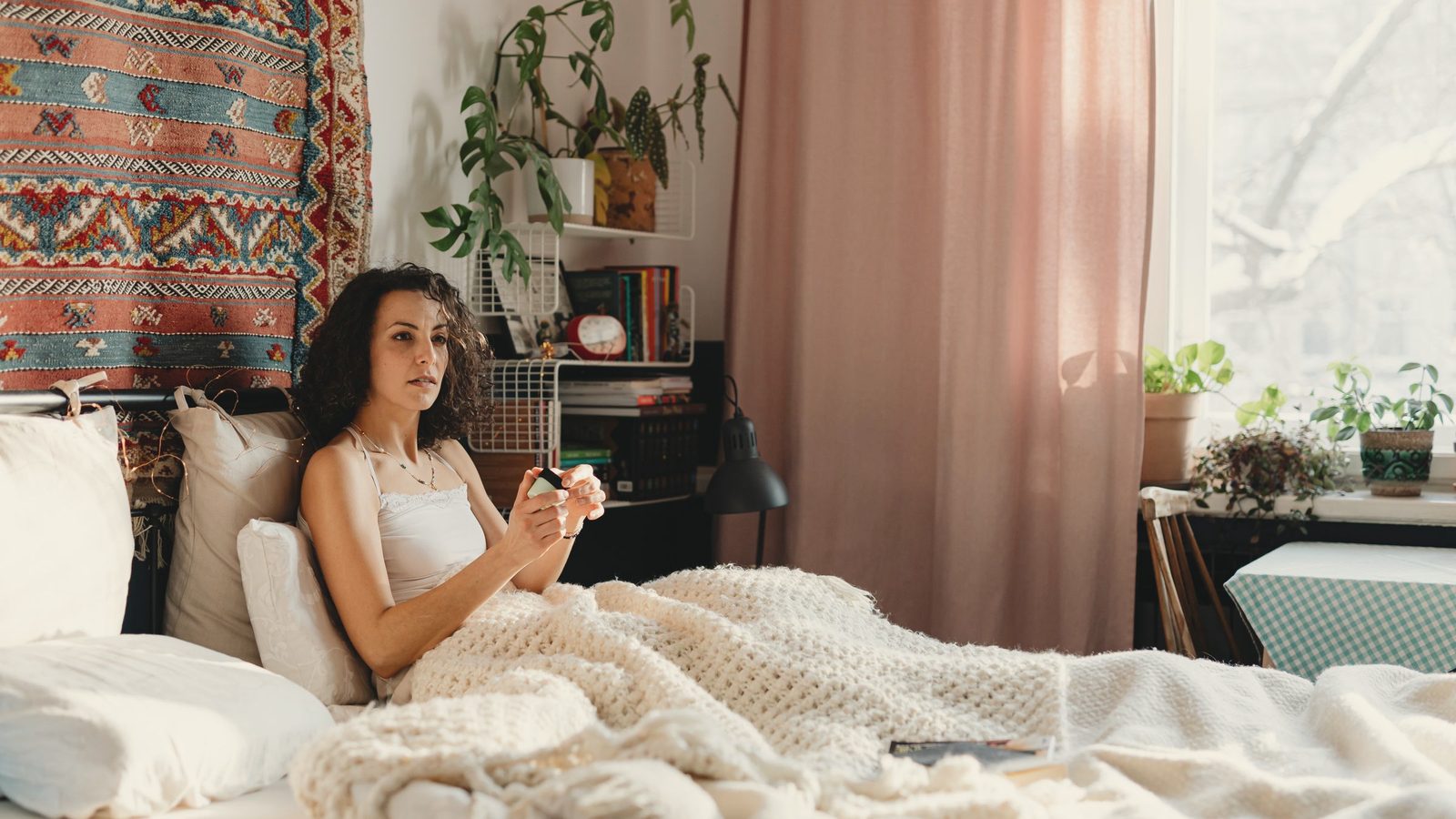 Woman relaxing under blanket in bed