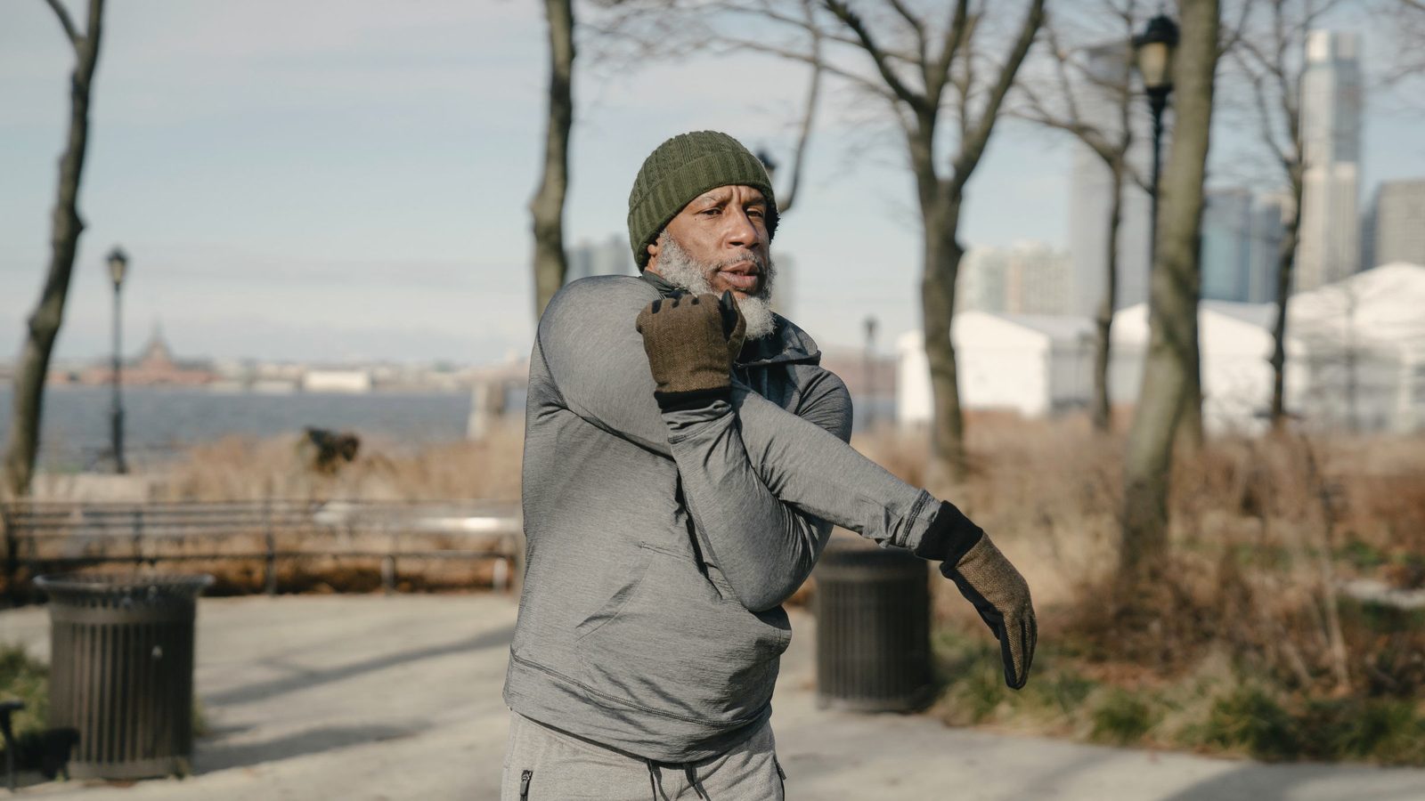 Senior man stretching his arm during morning exercise outdoors
