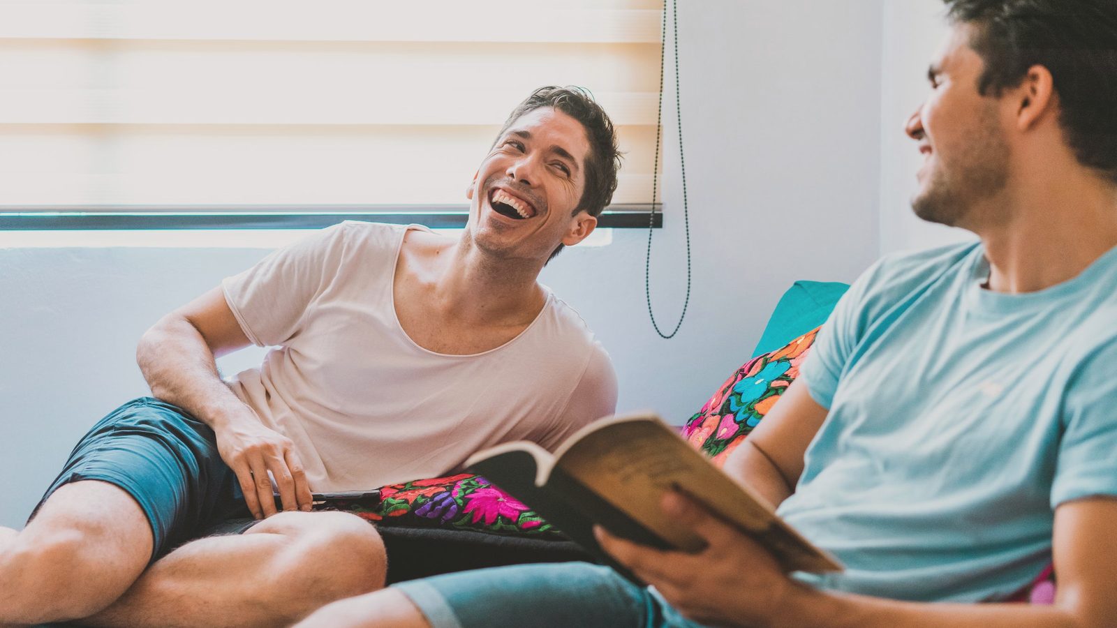 Two friends laughing together on a sofa