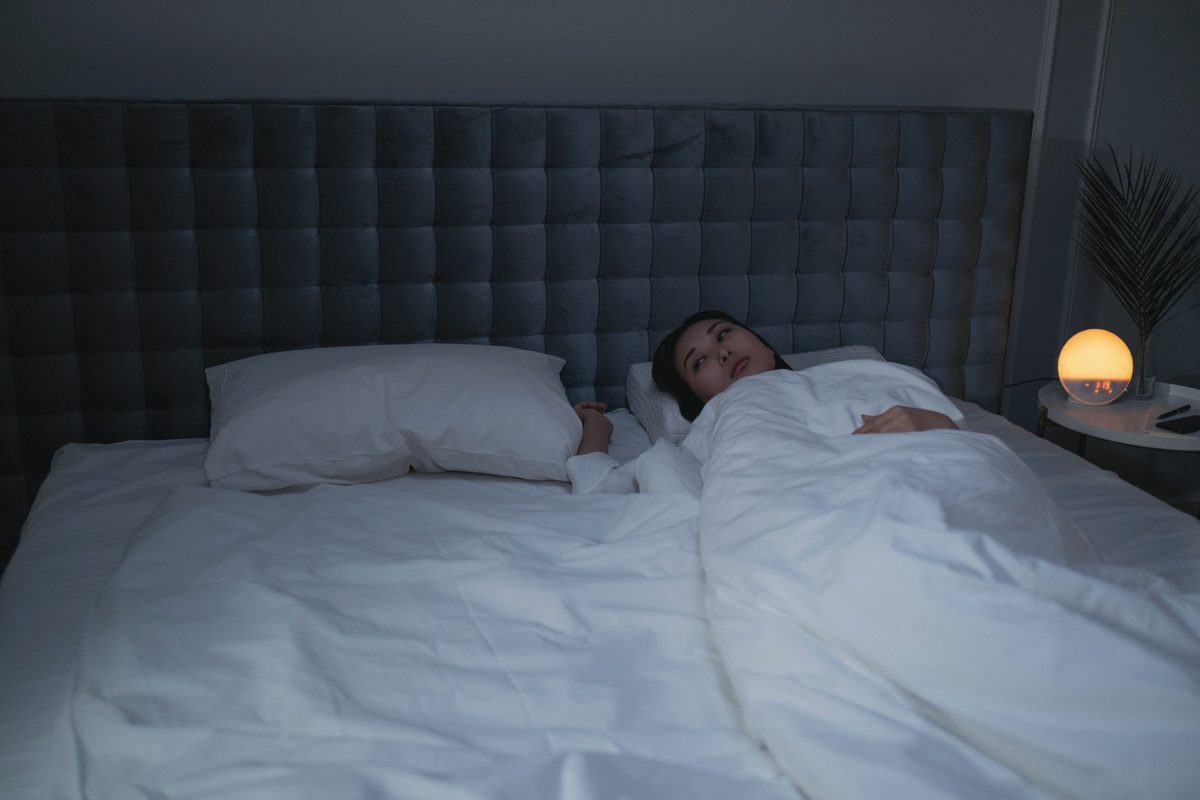 Woman lying on her bed in a dim bedroom