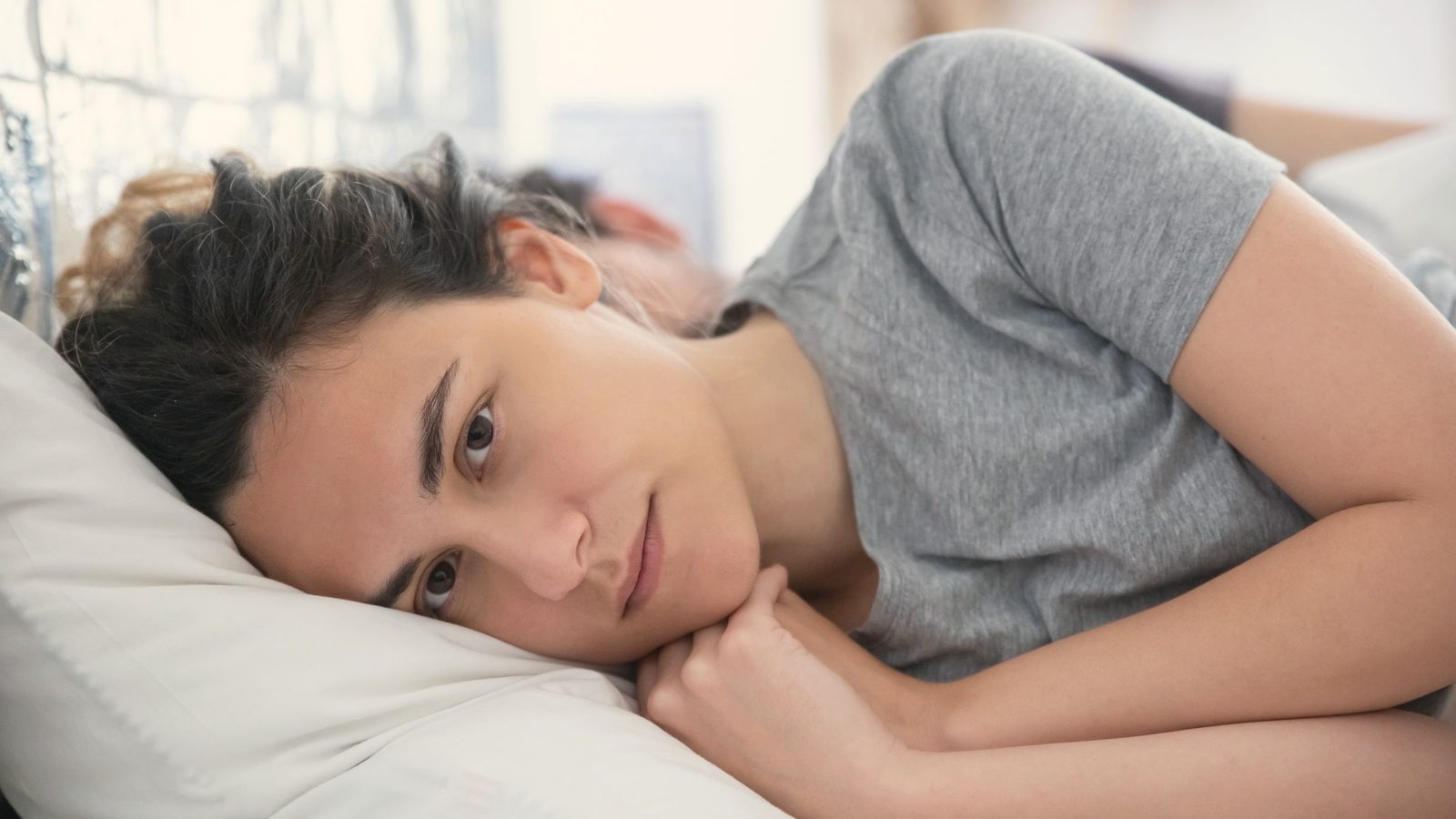 Woman in grey shirt lying on bed