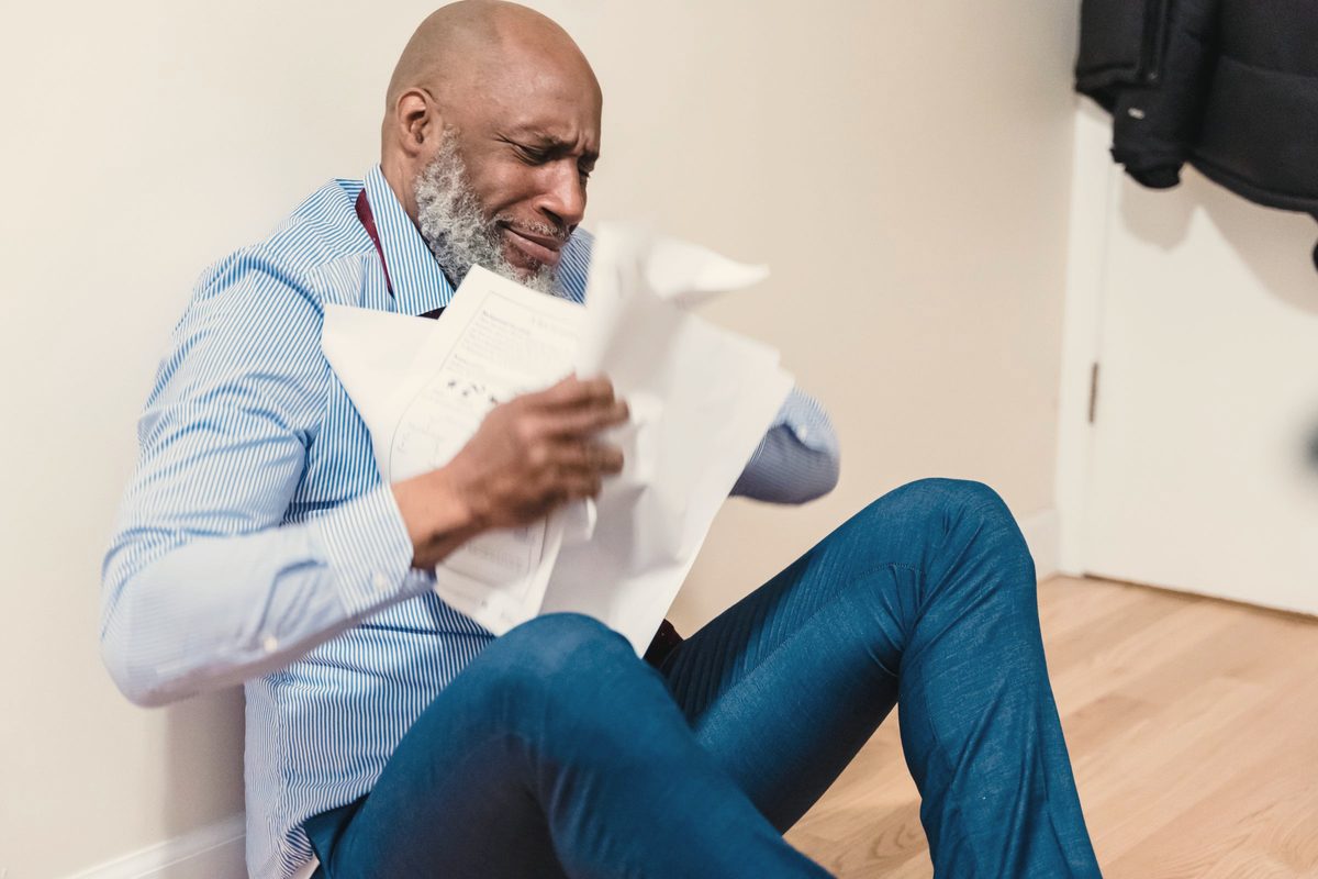 Frustrated older man reading paperwork at home
