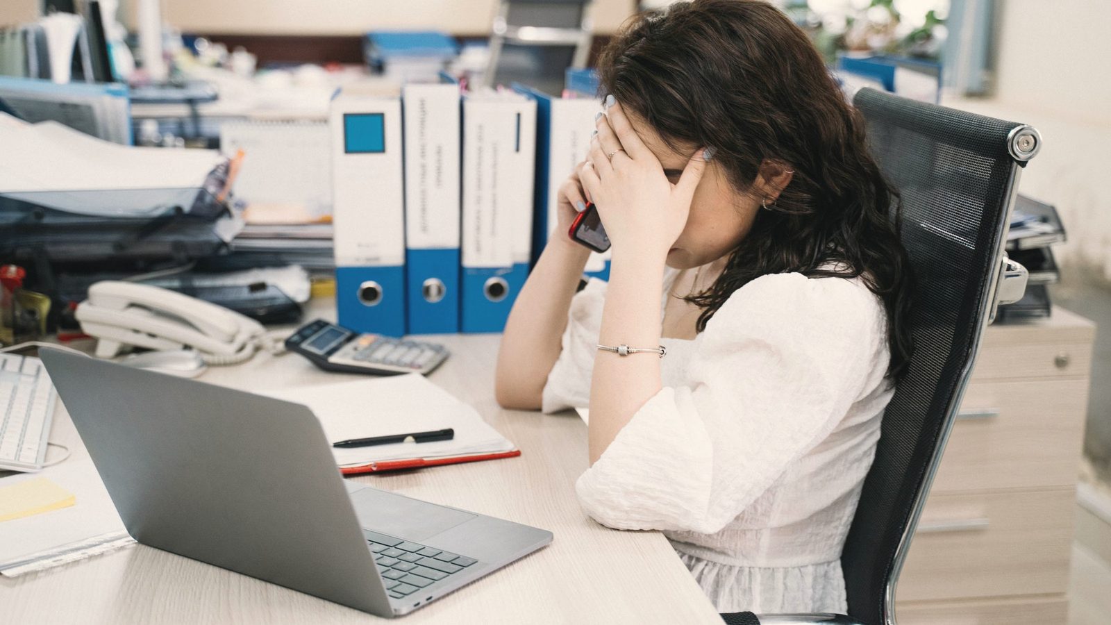 Stressed woman on a phone call at her office desk