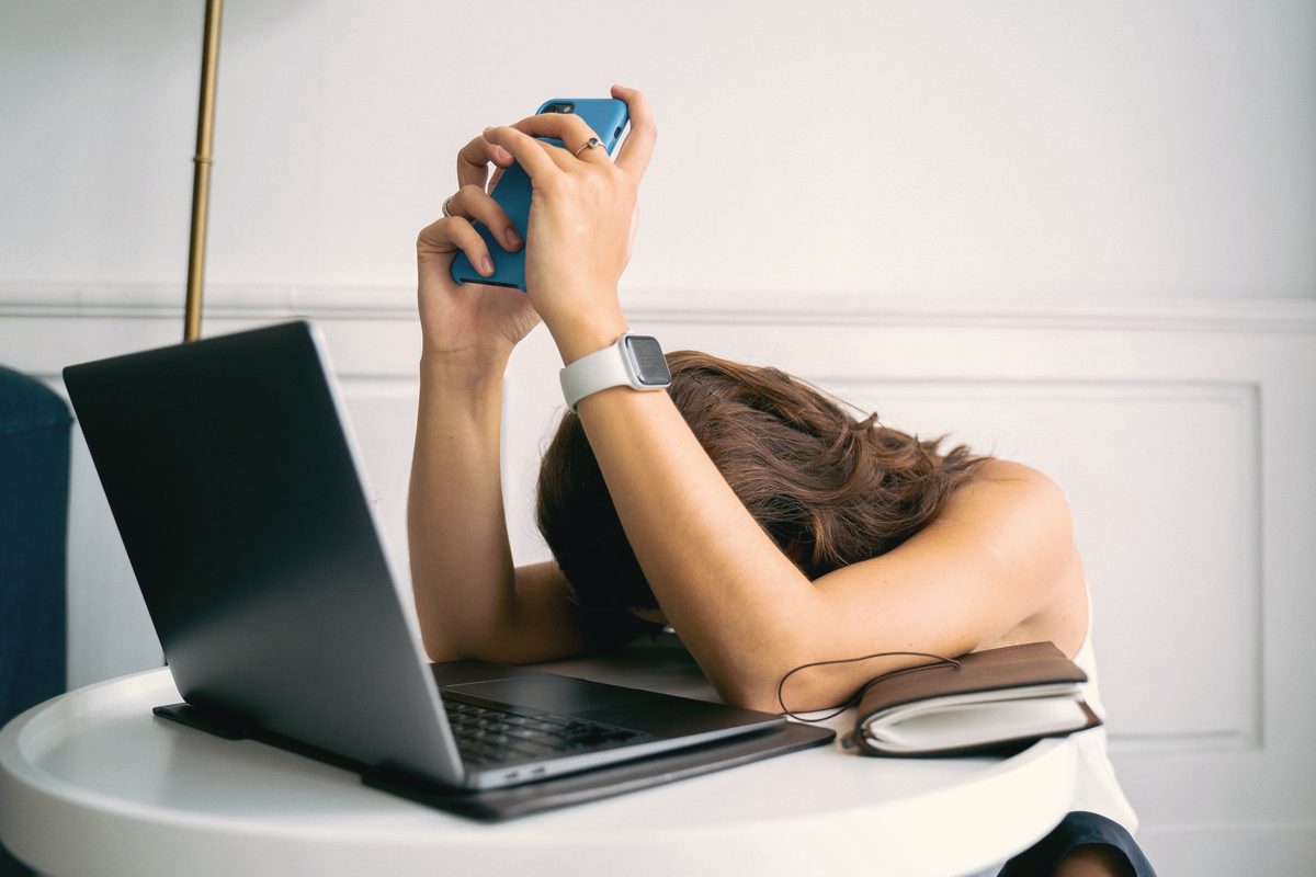 A woman wearing a smartwatch holding a smartphone