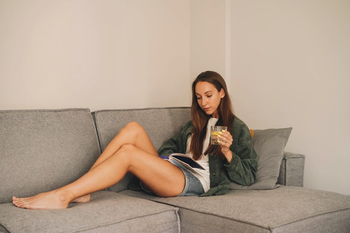 A woman reading a book on the sofa