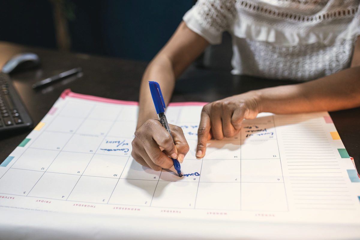 Person writing on paper calendar