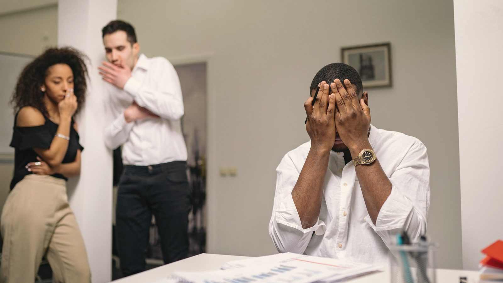 Overwhelmed man with his face in his hands at work