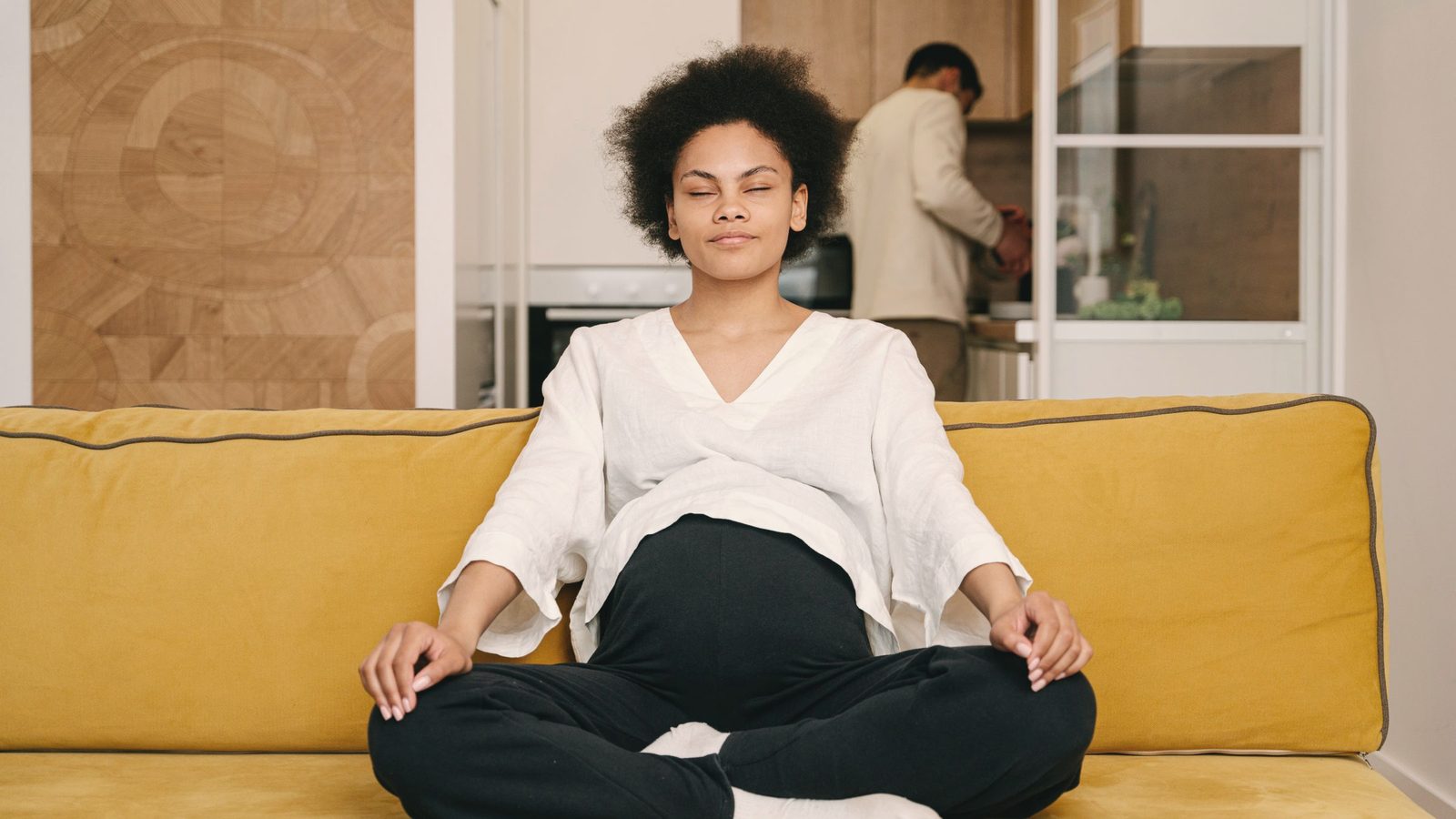 Woman meditating on a yellow sofa