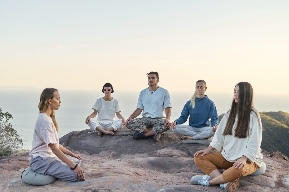 Group sitting cross-legged in quiet meditation by the sea