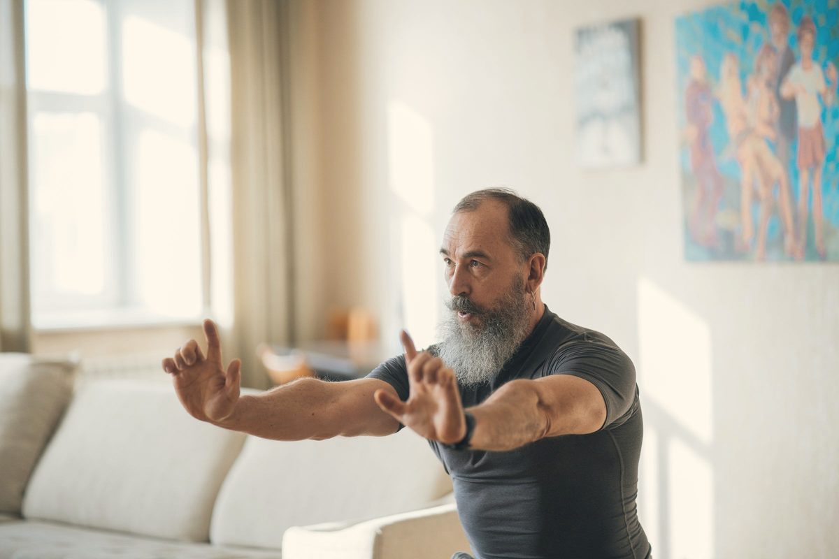 Older man doing slow breathing movements at home