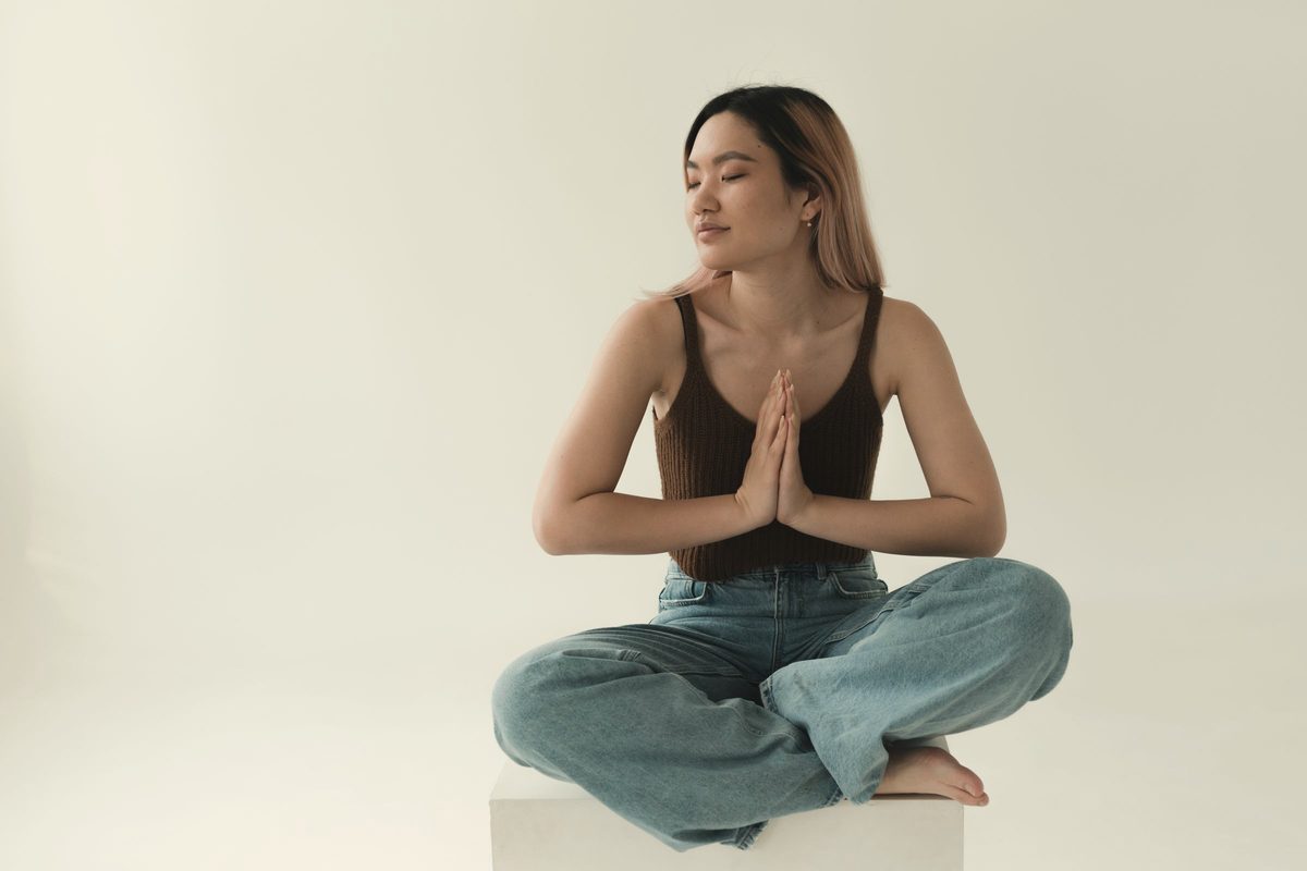 Woman sitting cross-legged with her palms pressed together