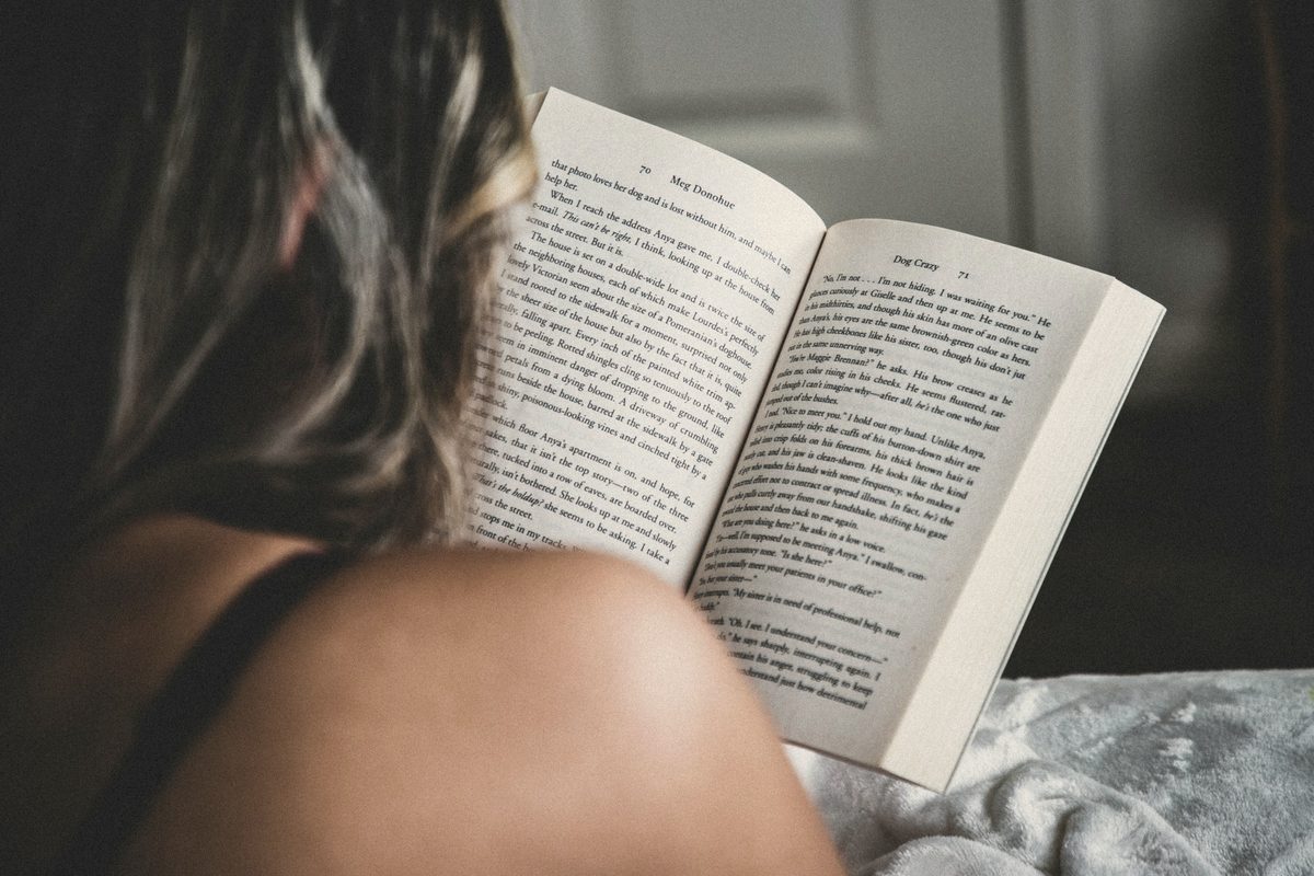 Person reading book on bed