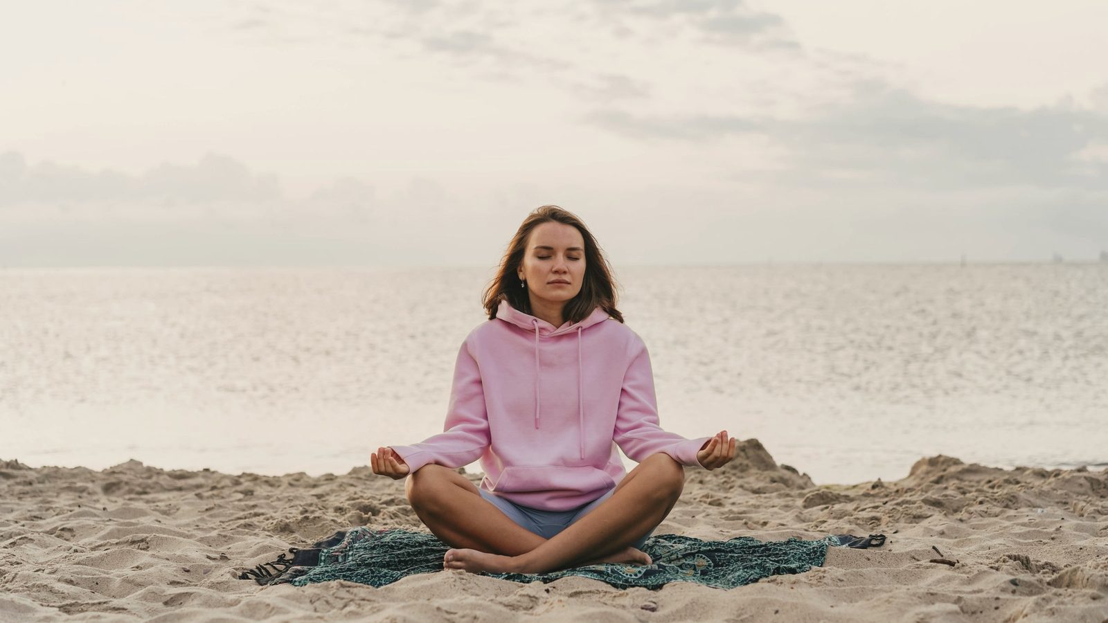 Woman meditating on the beach in the morning