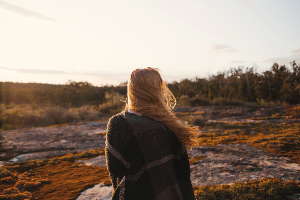 A woman wrapped in blanket looking at the landscape during sunrise