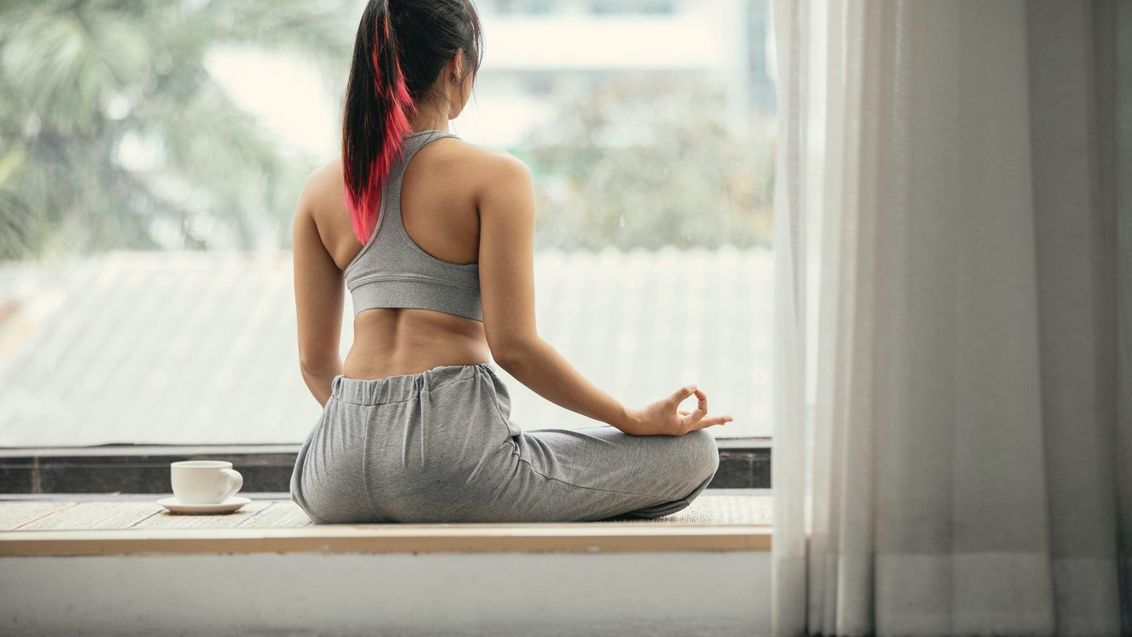Woman sitting cross-legged in meditation by the window